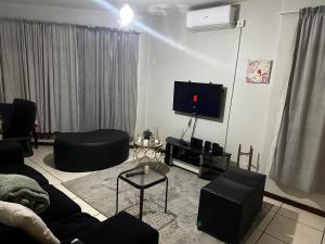 a living room with a couch and a flat screen tv at Feel At Home Cosy Apartment in Gaborone