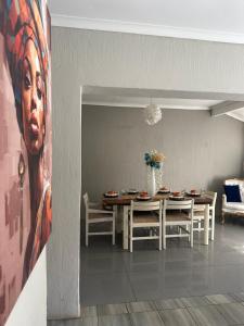 un comedor con una mesa y una pintura de una mujer en casa bella, en Hartbeespoort