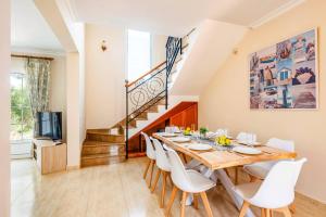 un comedor con una larga mesa de madera y sillas blancas en Villa Manuel by Villa Plus, en Son Parc