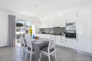 Una cocina con mesa y sillas y una cocina con gabinetes blancos. en Villa Dona Leonor by Villa Plus, en Carvoeiro