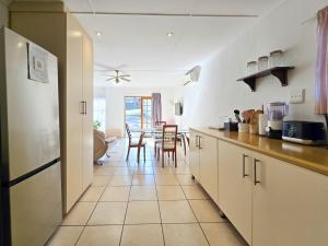una cucina con mobili bianchi e un tavolo con sedie di Coastal Retreat a East London