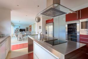 a kitchen with red and white cabinets and a stove at Villa Amadores con piscina privada in Mogán