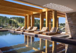 a row of lounge chairs next to a swimming pool at Viceroy Kopaonik Serbia in Kopaonik