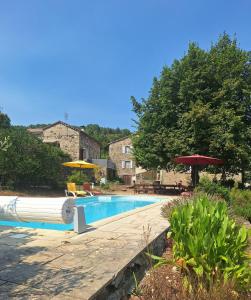 a swimming pool with umbrellas and chairs at Maison en pierre avec piscine in Ribes