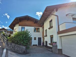 a white house with a wooden roof and a garage at Gästeheim Lederle in Jerzens