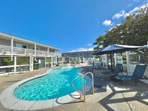 a swimming pool with an umbrella and chairs at Monterey Bay Lodge in Monterey