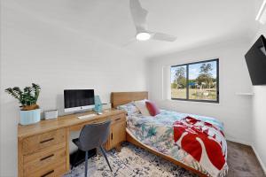 KurabyにあるSpacious 3 bedroom townhouse with patio and poolのベッドとパソコン付きの机がある寝室