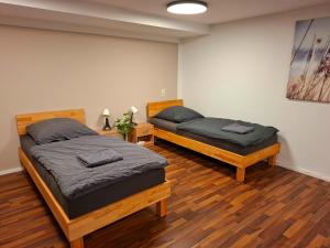 two beds in a room with wooden floors at Gemütliches Apartment in Giengen an der Brenz