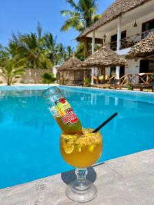 a drink sitting on a table next to a pool at Pamoja Villas in Migogoni