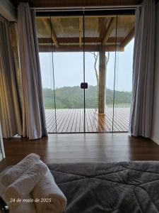 ランショ・ケイマードにあるTiny House em Taquaras, Rancho Queimadoのベッドルーム1室(デッキに面した大きなガラスドア付)