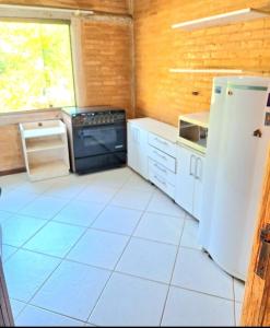 a kitchen with a refrigerator and a white tile floor at Loft charmoso! in Água Boa