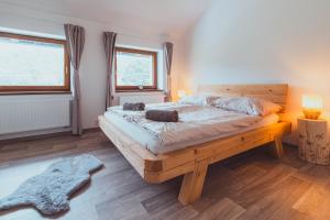 a bedroom with a large wooden bed with two windows at DOMEK Písařov - apartmány in Písařov