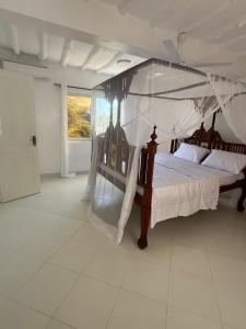 ein Schlafzimmer mit einem großen Bett mit Baldachin in der Unterkunft Mambrui Holiday Villa Nyumba Nane in Malindi