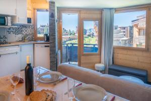 a living room with a couch and a table with a bottle of wine at Studio cabine vue montagne au pied des pistes & commerces in Avoriaz