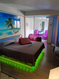 a bedroom with a bed and a living room with pink chairs at Hotel Puerto Angel in Ciudad Nezahualcóyotl +32 photos