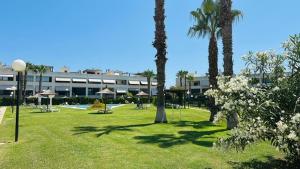 a park with palm trees and benches and a building at Calma y Golf in Santa Faz