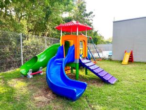 a playground with a slide in a yard at Apartamento Inteiro - 2 Quartos com AC - Wifi 1000mb - Piscina - 1 Vaga de Garagem - Elevador - Sacada Gourmet - Indicado para Grupos, Hospedes a Trabalho, Família e Pets in Toledo