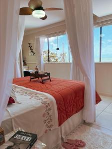 a bedroom with a bed with a red blanket and a window at Pousada Recanto da Família in Natal