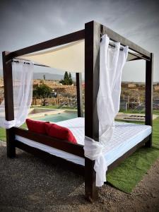 a bed with a canopy and curtains next to a pool at Finca La Suerte in Chimiche