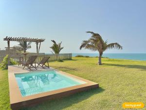 a swimming pool in a yard with two chairs and the ocean at Reserva BeachFront - Retirinho in Aracati