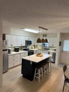 a kitchen with white cabinets and a large island with chairs at Sea the Good in Panama City Beach