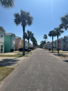 an empty street with palm trees and houses at Sea the Good in Panama City Beach