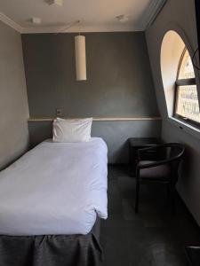 a bedroom with a bed and a chair and a window at Hotel Fundador in Santiago