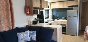 a kitchen with a couch and a kitchen with a refrigerator at Sfeervol chalet Renesse 3 slpk 2 badk airco in Renesse