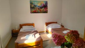 two beds in a room with a painting on the wall at Biały Domek Nielbark - Agroturystyka in Nielbark