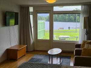 a living room with a large window with a view of a lake at Ikaalisten Kylpylä Apartamentos rantahuoneisto Terme in Ikaalinen