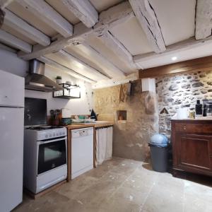 a kitchen with white appliances and a stone wall at L'échappée en Sologne in Mennetou-sur-Cher
