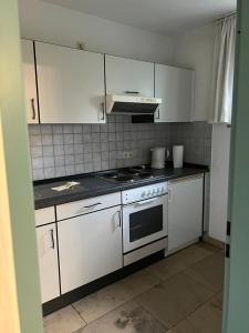 une cuisine avec des armoires blanches et un four à plaques de cuisson dans l'établissement Ruhiges Apartment in Dresdner Neustadt, à Dresde