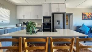 a kitchen with a large island in a kitchen with chairs at Nivica Lifestyle Apartment in Langebaan