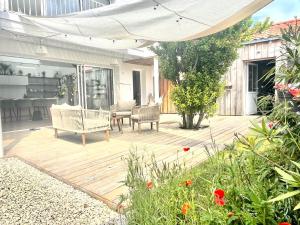 a wooden patio with chairs and a table and a table at La Petite Cabine, 3chambres proche plage et centre in Les Sables-dʼOlonne +20 photos