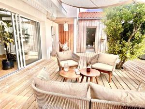 a patio with a couch and chairs on a wooden deck at La Petite Cabine, 3chambres proche plage et centre in Les Sables-dʼOlonne