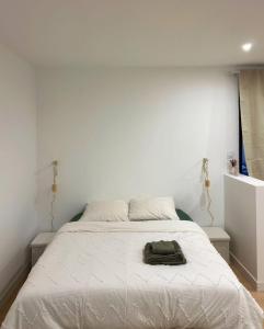 a white bedroom with a bed with a hat on it at Charmant T1 bis in Mérignac