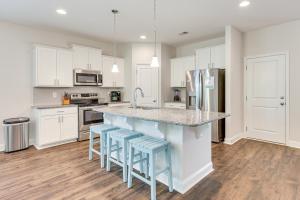a kitchen with white cabinets and a counter with blue stools at 3 Mi to Sand! Ocean Isle Beach Escape Near Golf in Seaside