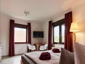 a hotel room with a bed and a desk and windows at Haus Freigeist - zum Gartenblick in Neinstedt +2 photos