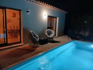 a swimming pool with two chairs next to a house at Location Saisonnière Villa in Uzès