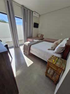 a bedroom with a bed and a chair and a window at Pousada Lobo Guará in São João Batista do Glória