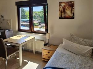 a room with a desk and a bed and a table and a window at Haus Freigeist - zum Wanderer in Neinstedt