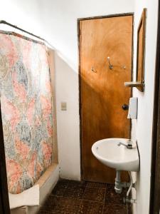 a bathroom with a sink and a wooden door at Hostal Casa del Sol in Suchitoto