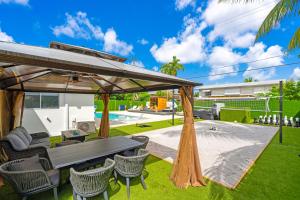 Un patio trasero con una mesa de picnic y sillas y una piscina. en Miami Resort Villa - Volleyball - Jacuzzi - Sauna, en Ives Estates