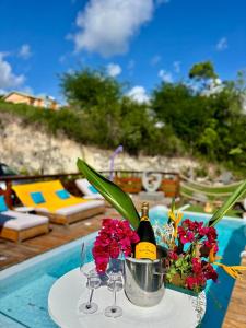 einen Tisch mit einem Eimer Blumen und einer Flasche Champagner in der Unterkunft Villa Iséa - Piscine privée & Terrasse Vue Mer in Le Gosier