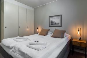 a bedroom with a large white bed with two towels at Villa Santa's Star I near SCV in Rovaniemi