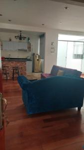 a living room with a blue couch and a kitchen at Excelente Departamento las viñas in La Molina