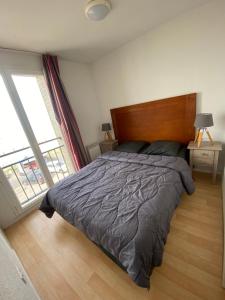 a bedroom with a large bed and a large window at L'élégance du Large in Cayeux-sur-Mer