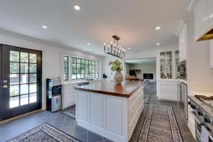 LouisburgにあるGame Room and Pool! Luxe Louisburg Farmhouseの白いキャビネットと大きな島のある広いキッチンが備わります。