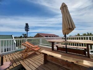 a wooden deck with an umbrella and a table and a bench at 8 Eden Villa in Yzerfontein