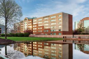 un edificio con la sua riflessione in un corpo idrico di Elimwood Hotel, a Ramada by Wyndham a Maryland Heights